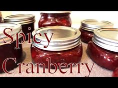 some jars filled with red liquid sitting on top of a wooden table and the words spicy cranberry