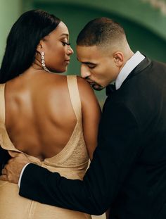 a man in a tuxedo and a woman in a gold dress embracing each other