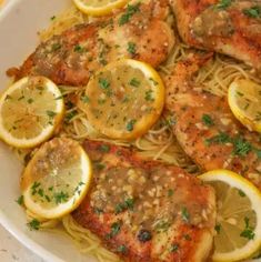 a white bowl filled with chicken and lemons on top of pasta covered in parmesan cheese