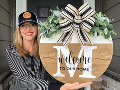 a woman holding up a welcome to our home sign