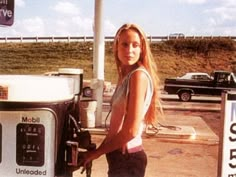 a woman standing next to a machine at a gas station