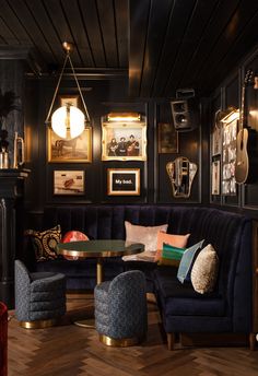 a living room with black walls and wooden flooring, blue couches and chairs