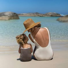 a woman and child sitting on the beach