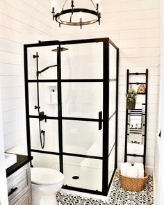 a white toilet sitting next to a shower in a bathroom under a chandelier