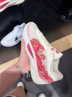 someone is wearing white and pink sneakers with roses on them