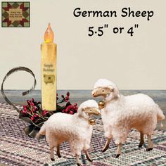 two white sheep standing next to a tall candle on a rug with other items around it