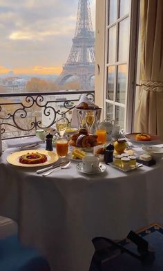 a table with food and drinks on it in front of the eiffel tower