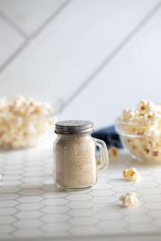 there is a bowl of popcorn and a glass jar with it on the counter top