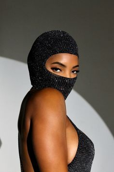 a woman in a black dress with a hood on her head and wearing a mask