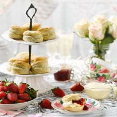 a table topped with plates filled with pastries and strawberries next to bowls of fruit