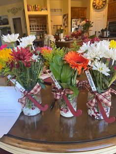 three vases filled with flowers sitting on top of a table