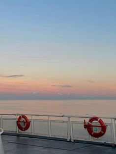 two life preservers are on the deck of a ship at sunset, with an ocean in the background