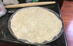 an uncooked pizza sitting on top of a counter next to a rolling pin