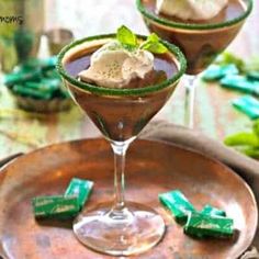 two martini glasses filled with chocolate and mint garnish on top of a plate