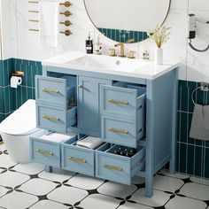 a white toilet sitting next to a blue sink in a bathroom with green tile on the walls