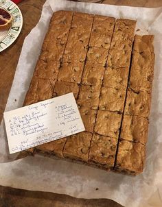 a bunch of brownies sitting on top of a table next to a piece of paper