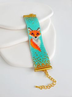 a gold chain bracelet with an owl beaded on it's side, sitting on top of a white plate