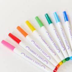 six different colored pens sitting next to each other on top of a white countertop