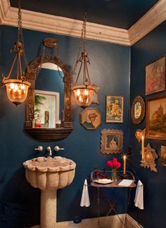 a bathroom with blue walls and pictures on the wall, including an ornate pedestal sink