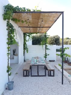 an outdoor dining area with table, benches and potted plants on the side wall