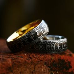 two gold and silver wedding bands sitting on top of a rock