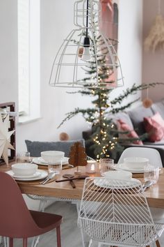 a dining room table set for christmas with plates and silverware on the placemats