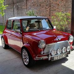 an old red car parked in front of a brick building