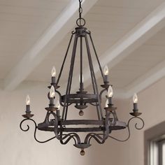 a chandelier hanging from the ceiling in a room with white walls and wood beams