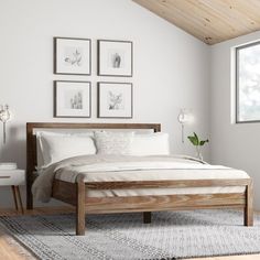 a bed sitting in a bedroom next to two framed pictures on the wall above it