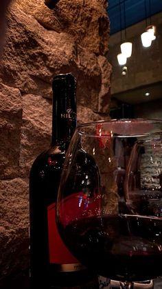 two wine glasses sitting next to each other on a table with rocks in the background