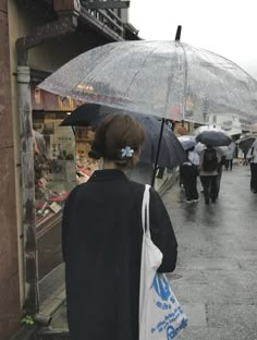 a woman with an umbrella is walking down the street on a rainy day in japan