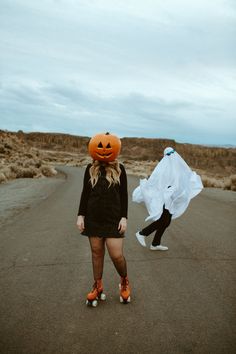 two women in black dresses and orange shoes are walking down the road with pumpkin hats on their heads