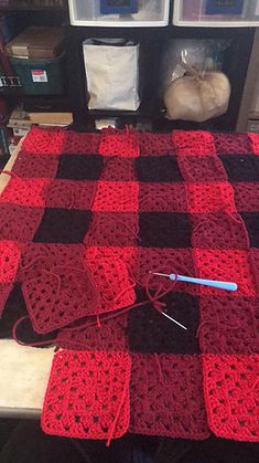 a red and black crocheted blanket sitting on top of a table