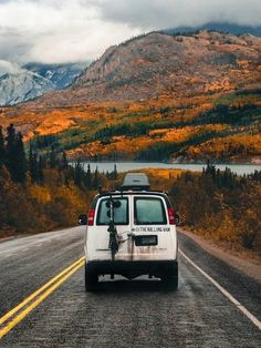 a white van driving down the road with mountains in the background