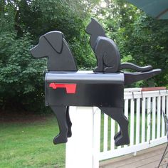 a mailbox shaped like a dog and a cat sitting on it's back