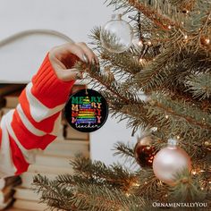 a person holding a christmas ornament in front of a christmas tree with ornaments