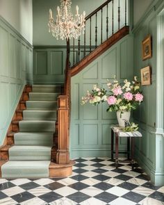 a room with green walls, stairs and flowers