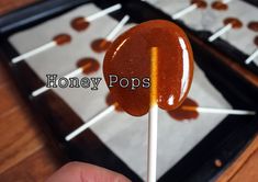 a hand holding a lollipop on a stick with the word honey pops above it