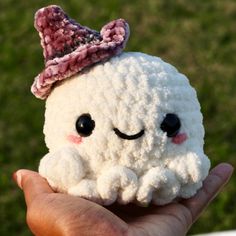 a hand holding a small white crocheted toy