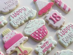 decorated cookies with pink and white frosting are arranged on a table top for a birthday party