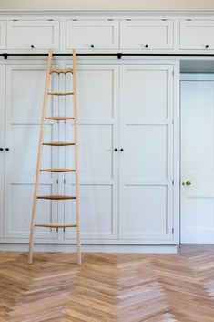 an empty room with white cupboards and a ladder