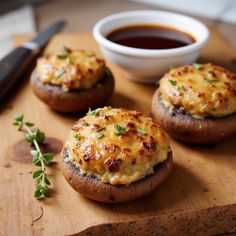 three stuffed mushrooms on a cutting board with dipping sauce