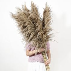 a woman holding a bunch of dry grass