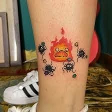 a small tattoo on the leg of a person with spider legs and fire in the background