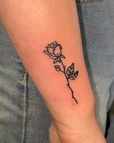 a woman's arm with a small rose tattoo on the left side of her arm