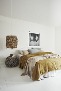 a bedroom with a bed, lamp and pictures hanging on the wall in front of it