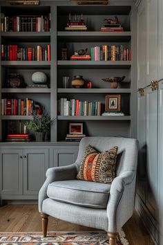 a grey chair sitting in front of a book shelf filled with books