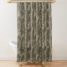 a camo shower curtain hanging on a gold rod in a bathroom with wood floors