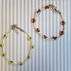 two bracelets with beads and charms on a striped tablecloth background, one has a beaded charm