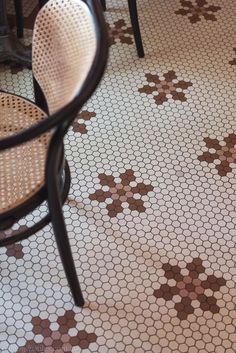 the floor is covered in brown and white tile with flowers on it, as well as two chairs